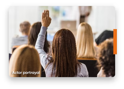 A woman raises her hand to ask a question during an educational event about multiple sclerosis amidst an engaged audience. Not real MAVENCLAD® (cladribine) patients.